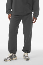 Person wearing a dark gray tracksuit with sneakers on a white background