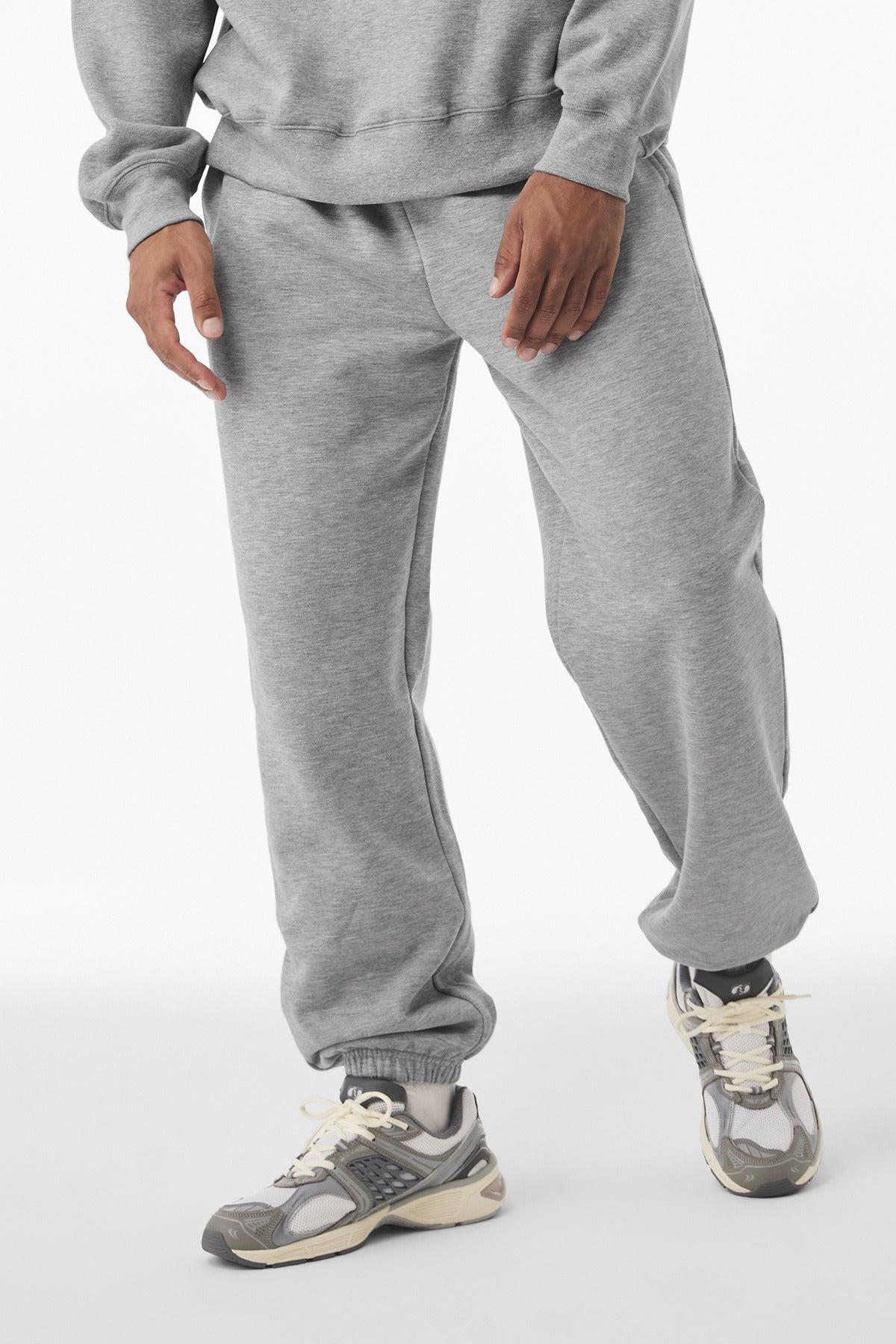Person wearing a gray tracksuit with sneakers on a white background