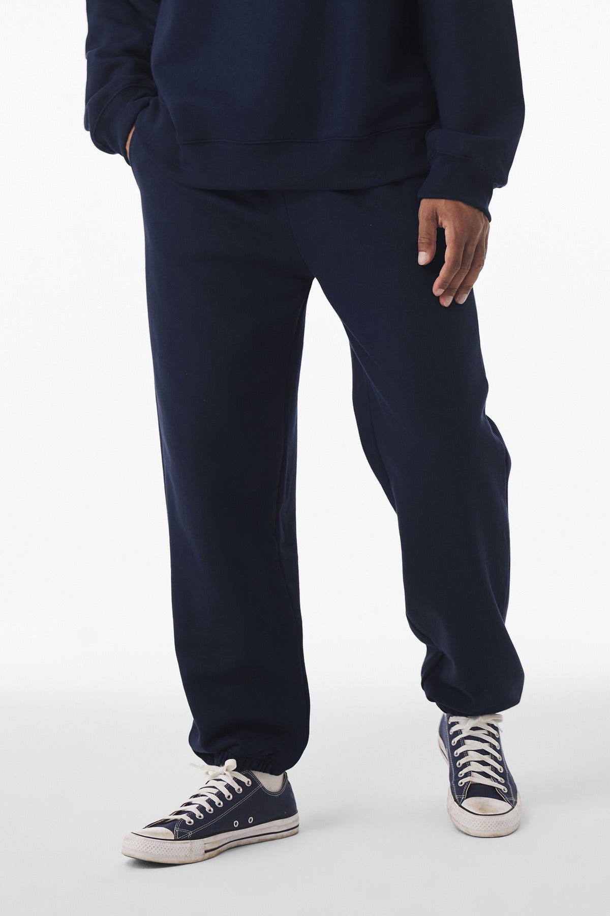Person wearing navy sweatpants and sneakers on a white background