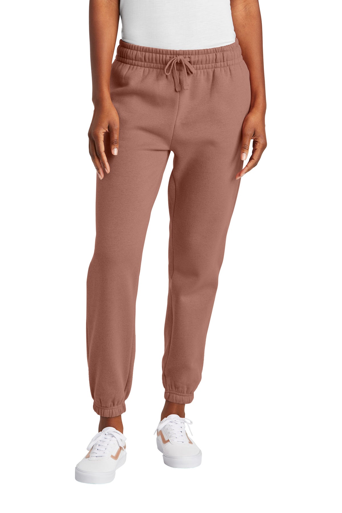 Person wearing brown jogger pants and white sneakers on a white background