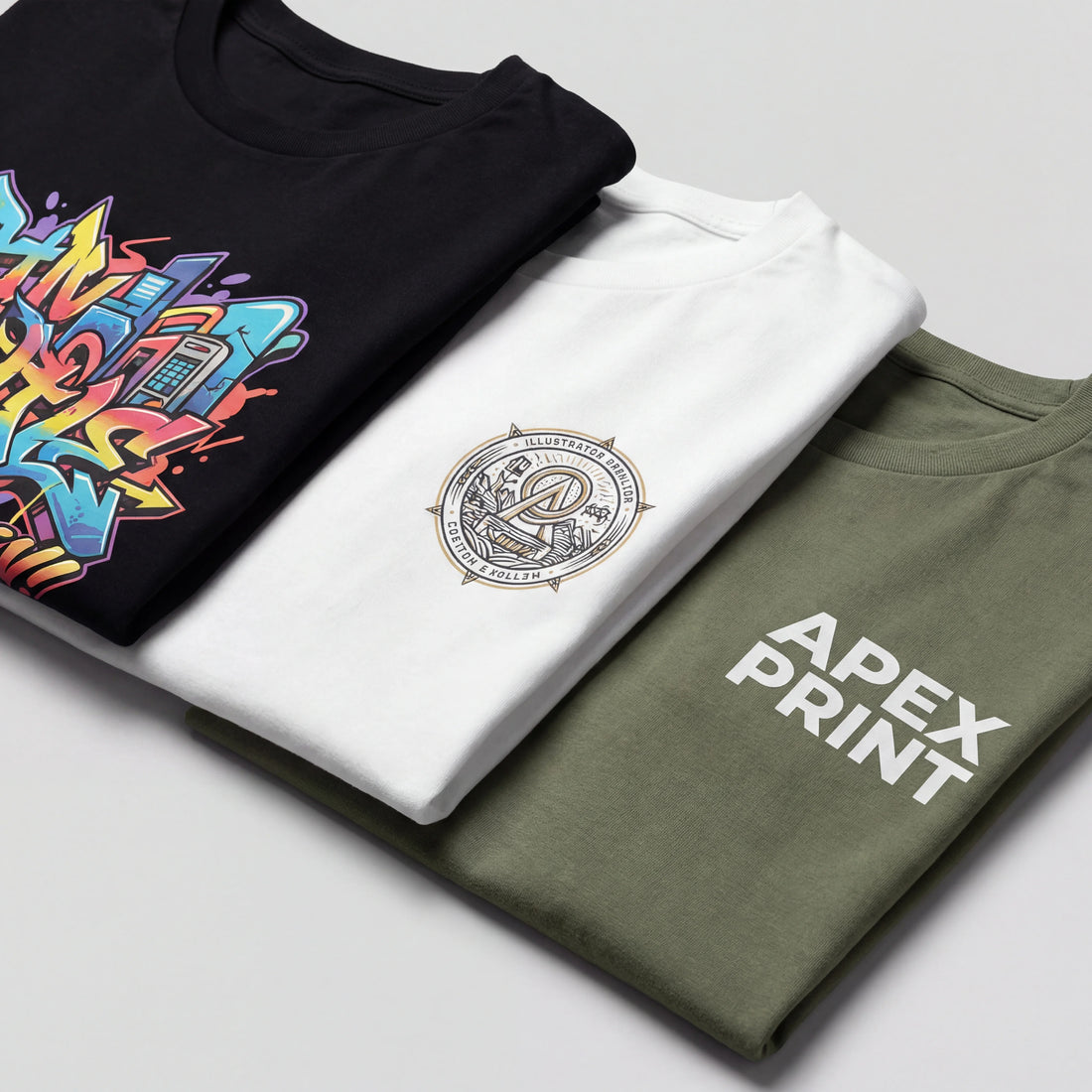 Three folded t-shirts with different prints on a light gray background