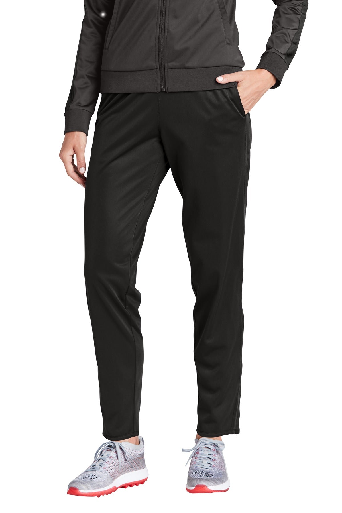 Person wearing a black tracksuit with gray shoes on a white background