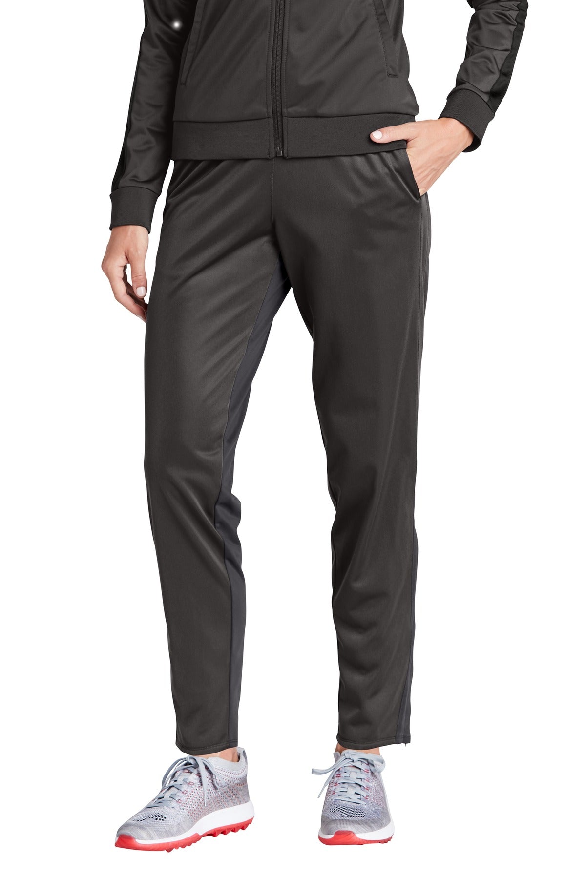 Person wearing a black tracksuit with gray shoes on a white background