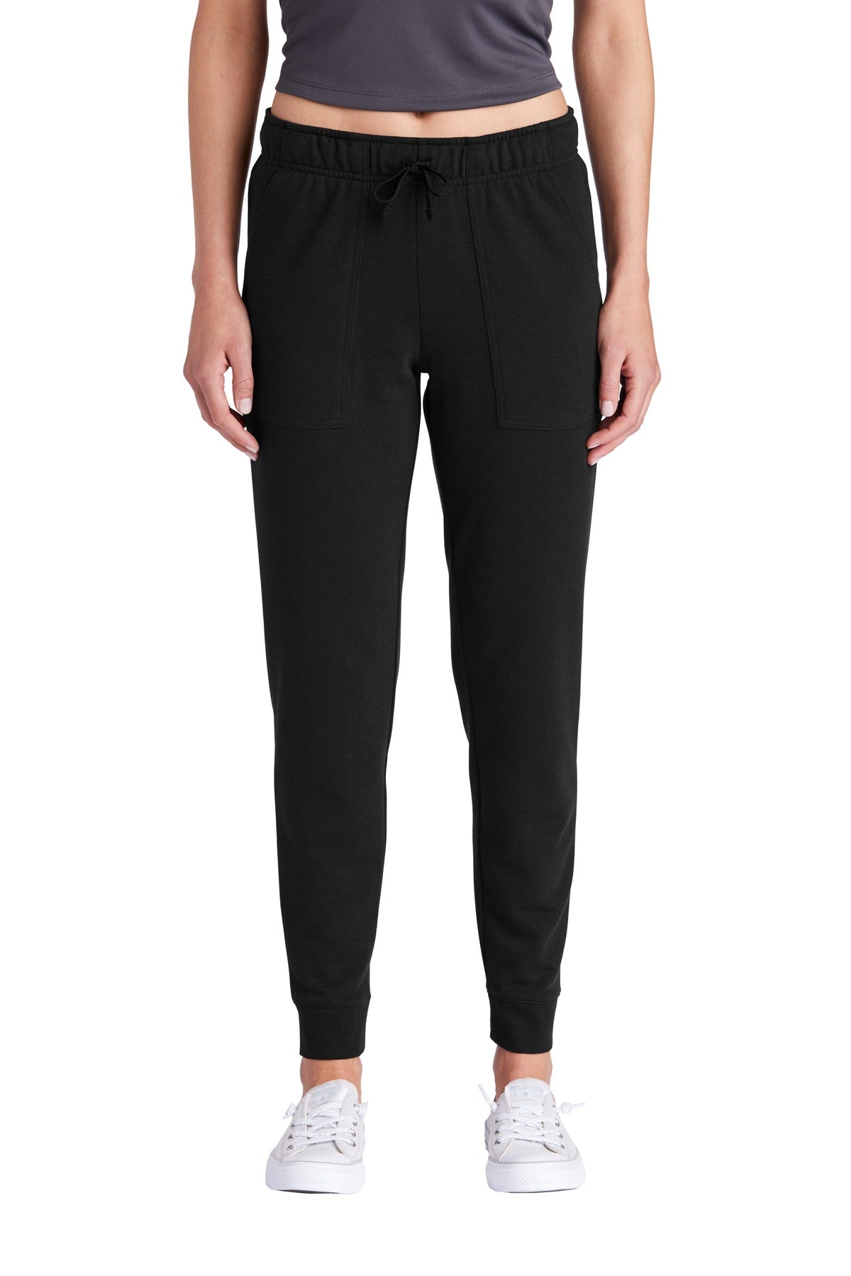 Person wearing black jogger pants and white sneakers on a white background