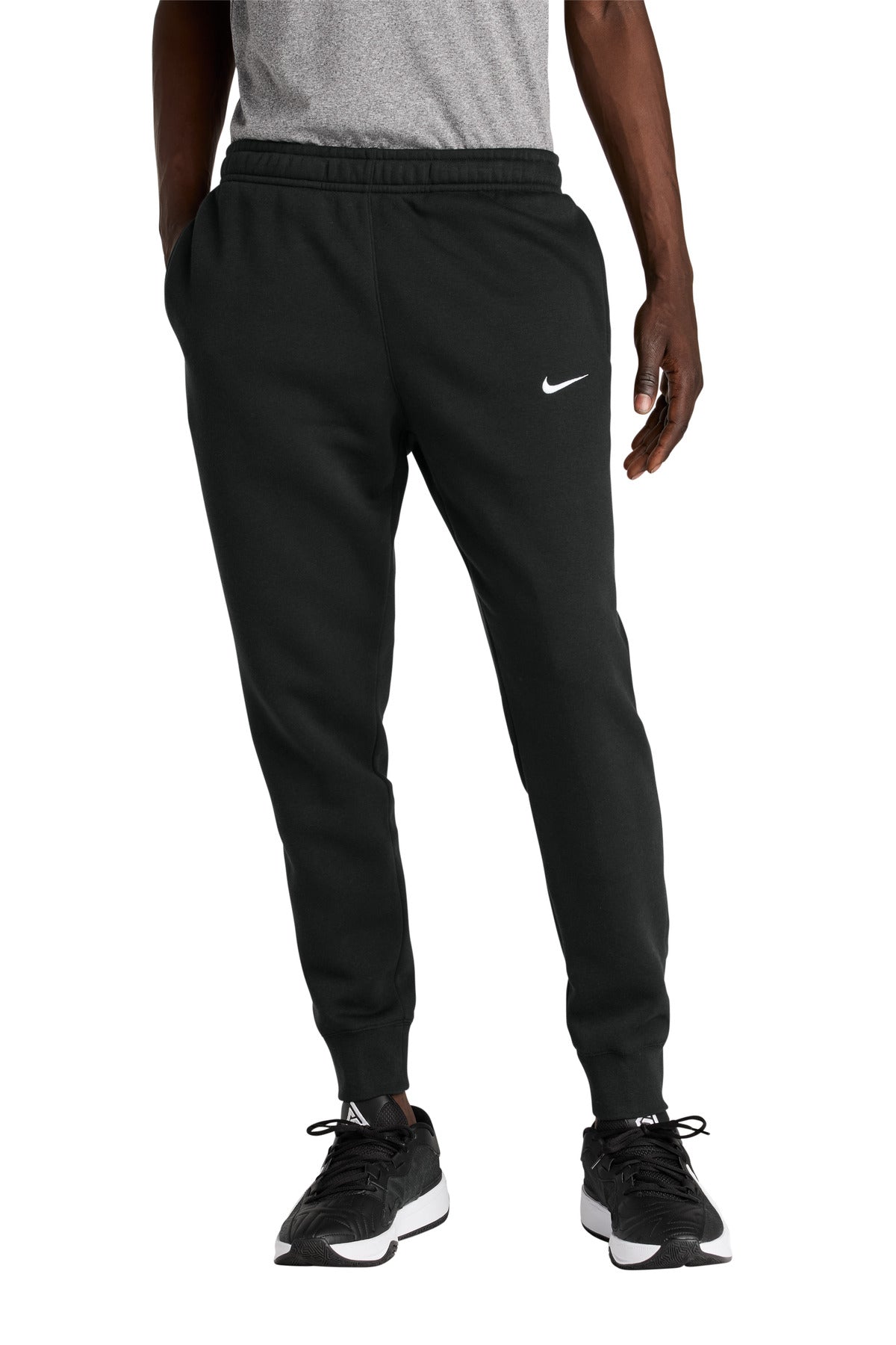 Person wearing black jogger pants with a logo and Nike branding on a white background