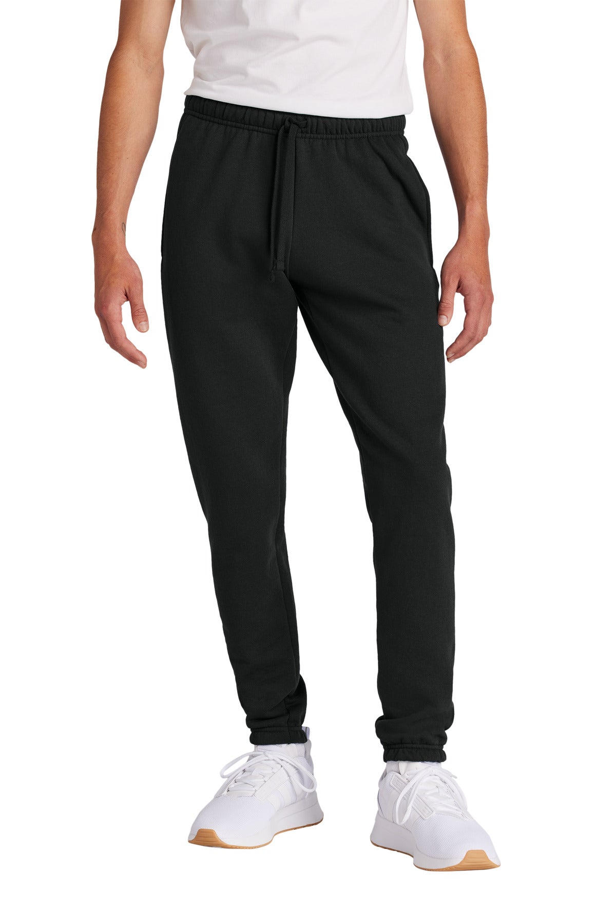 Person wearing black jogger pants and white sneakers on a white background