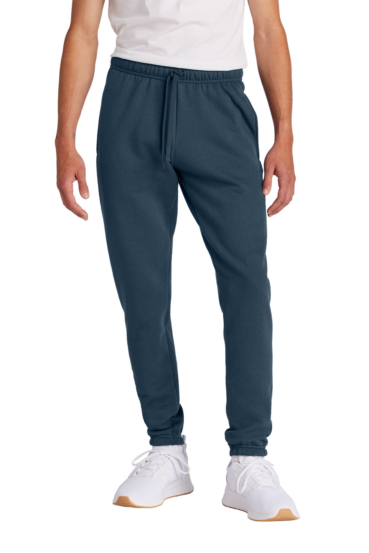 Person wearing blue jogger pants and white sneakers on a white background