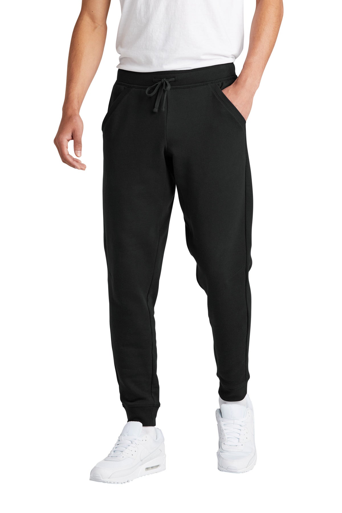 Person wearing black jogger pants and white sneakers on a white background