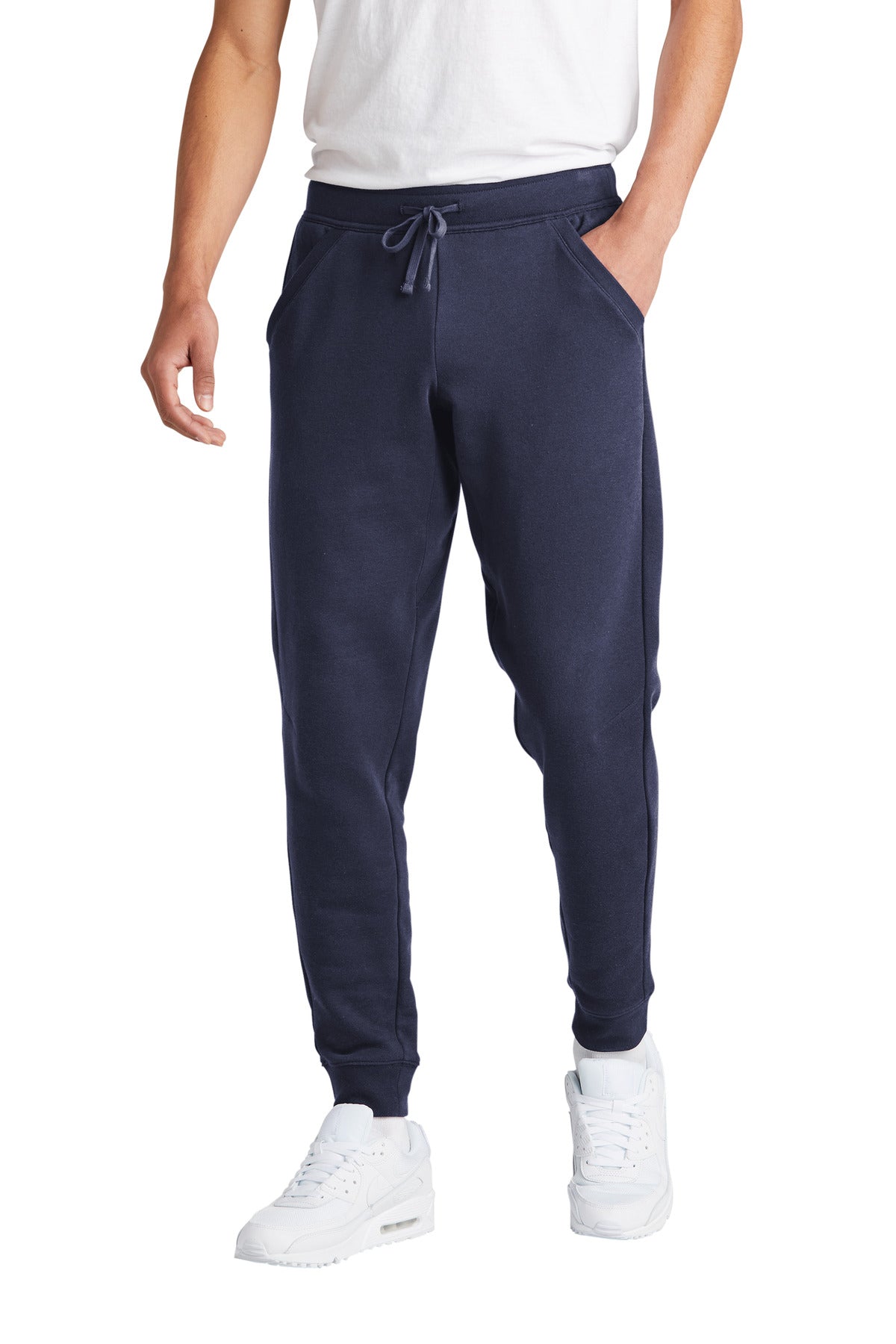Person wearing navy jogger pants and white sneakers on a white background